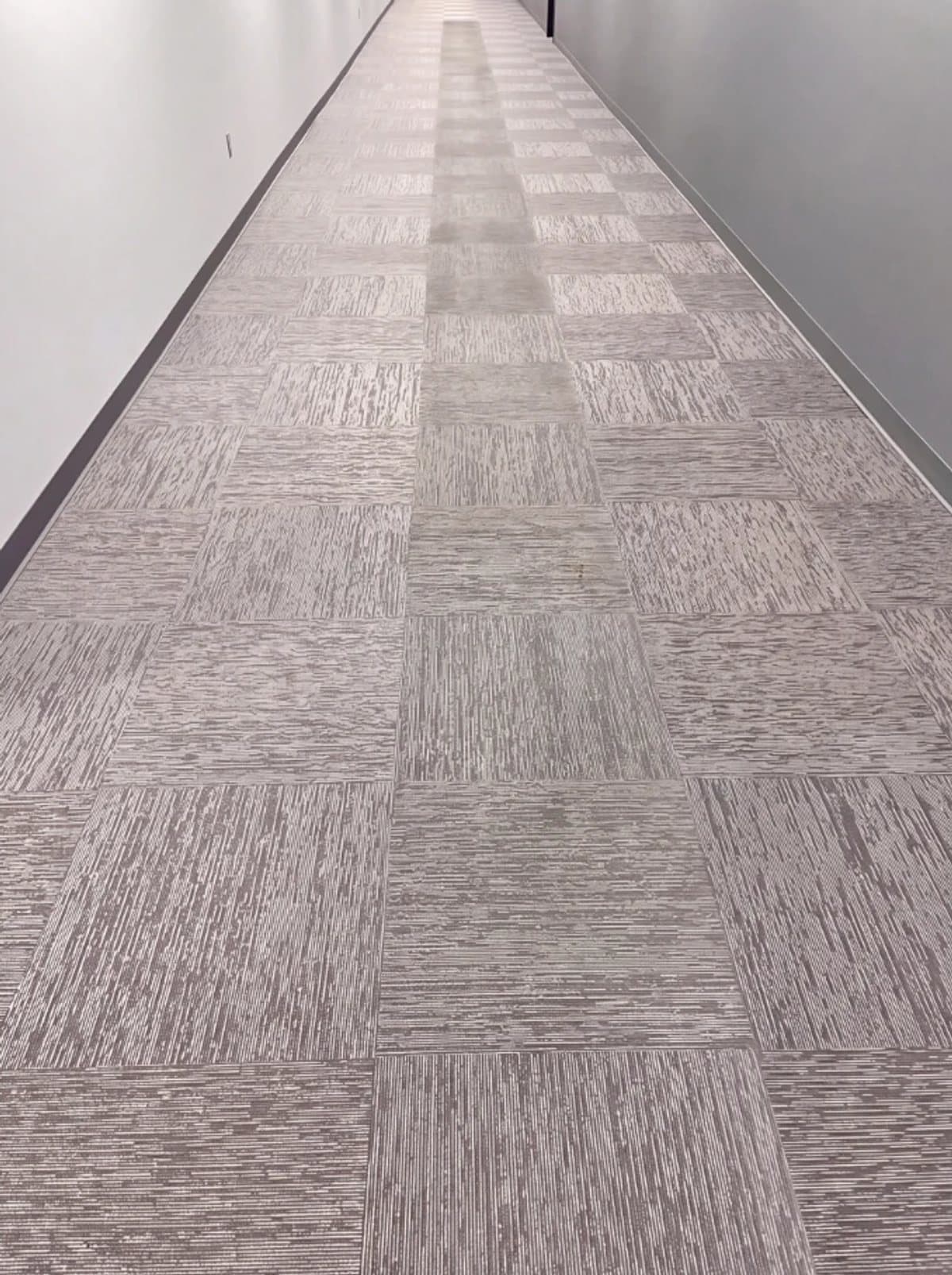 Illustrative example: an office corridor with a worn, dull traffic lane down the middle of the carpet, before cleaning