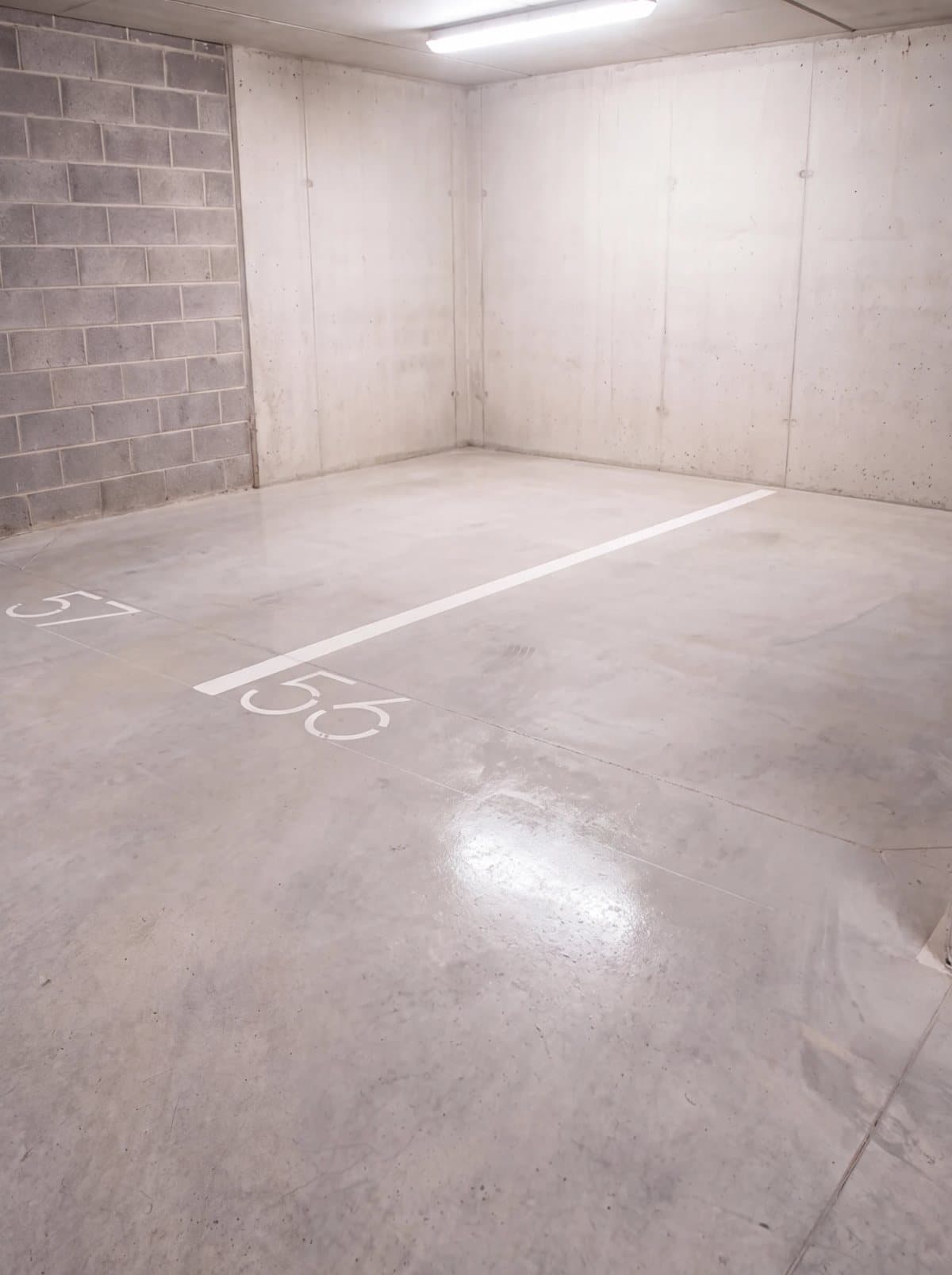 Illustrative example: the same car park corner with clean, bright concrete after pressure washing