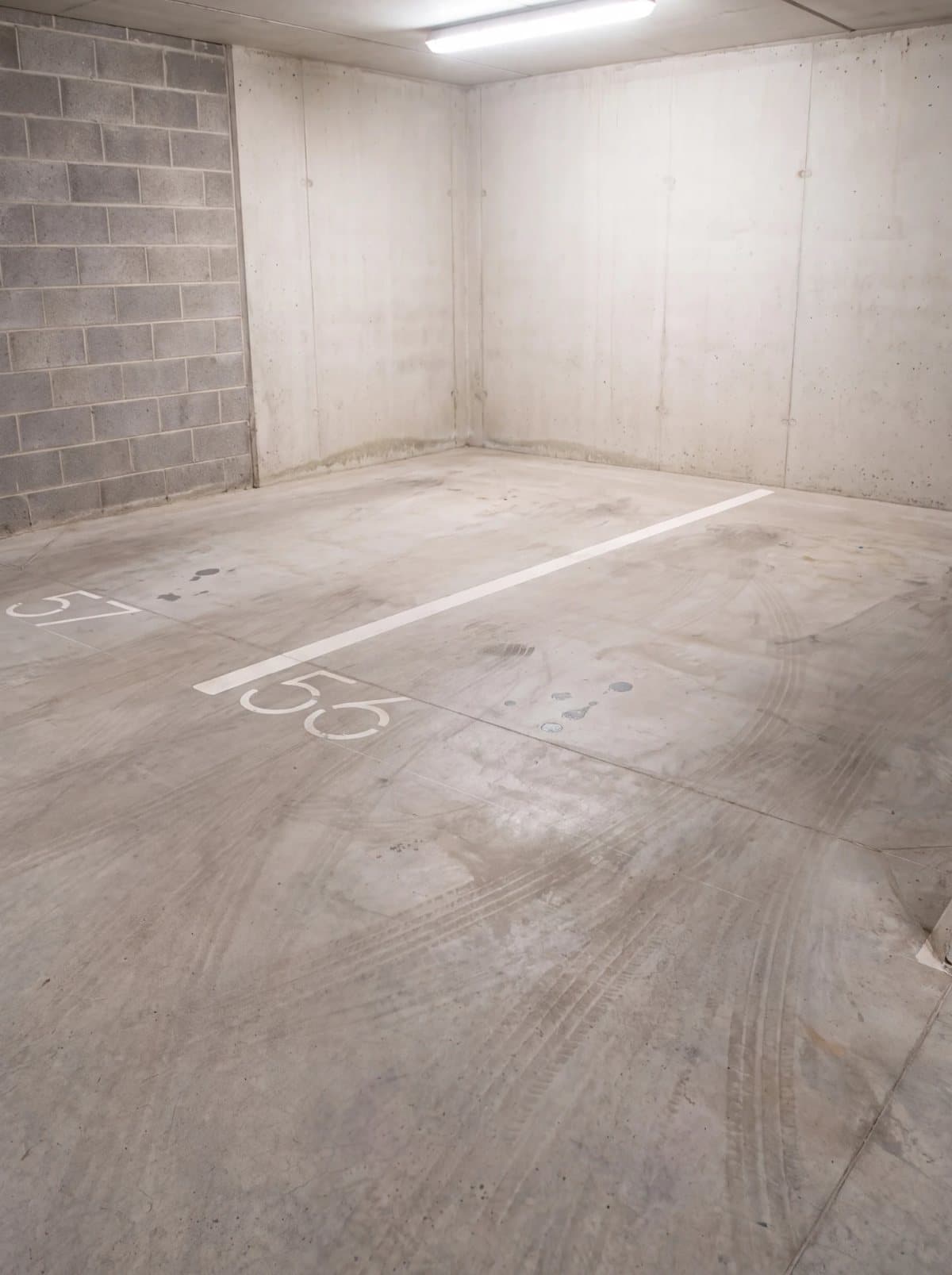 Illustrative example: a car park corner with grimy concrete, tyre marks and oil drips, before pressure washing