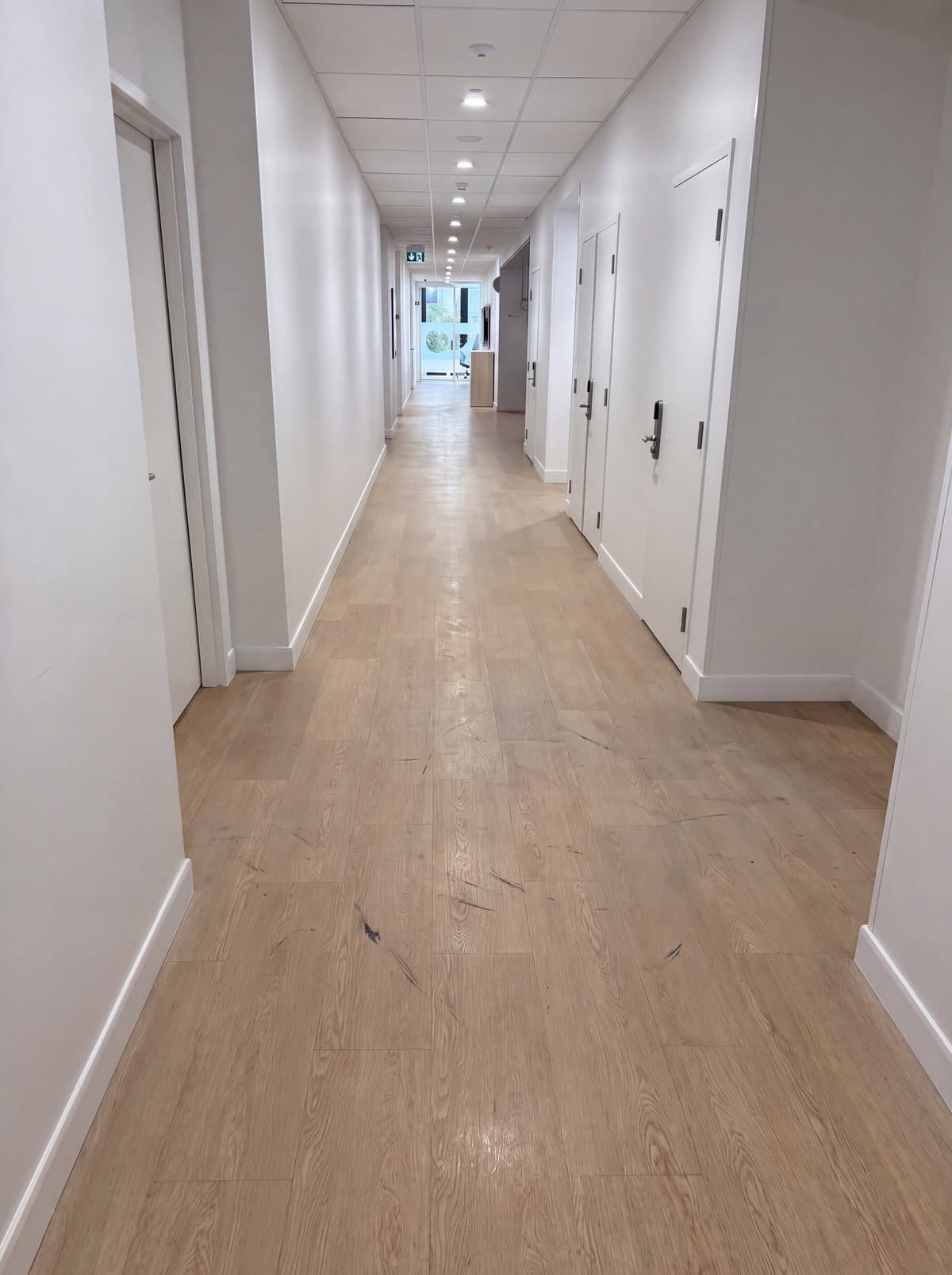 Illustrative example: a commercial corridor with a dull, scuffed vinyl floor and a dirty build-up along the edges, before strip and seal