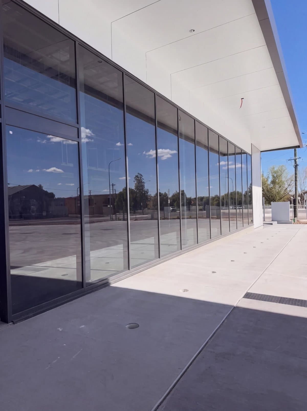 Illustrative example: the same glass shopfront with clean, clear windows reflecting the sky, after cleaning