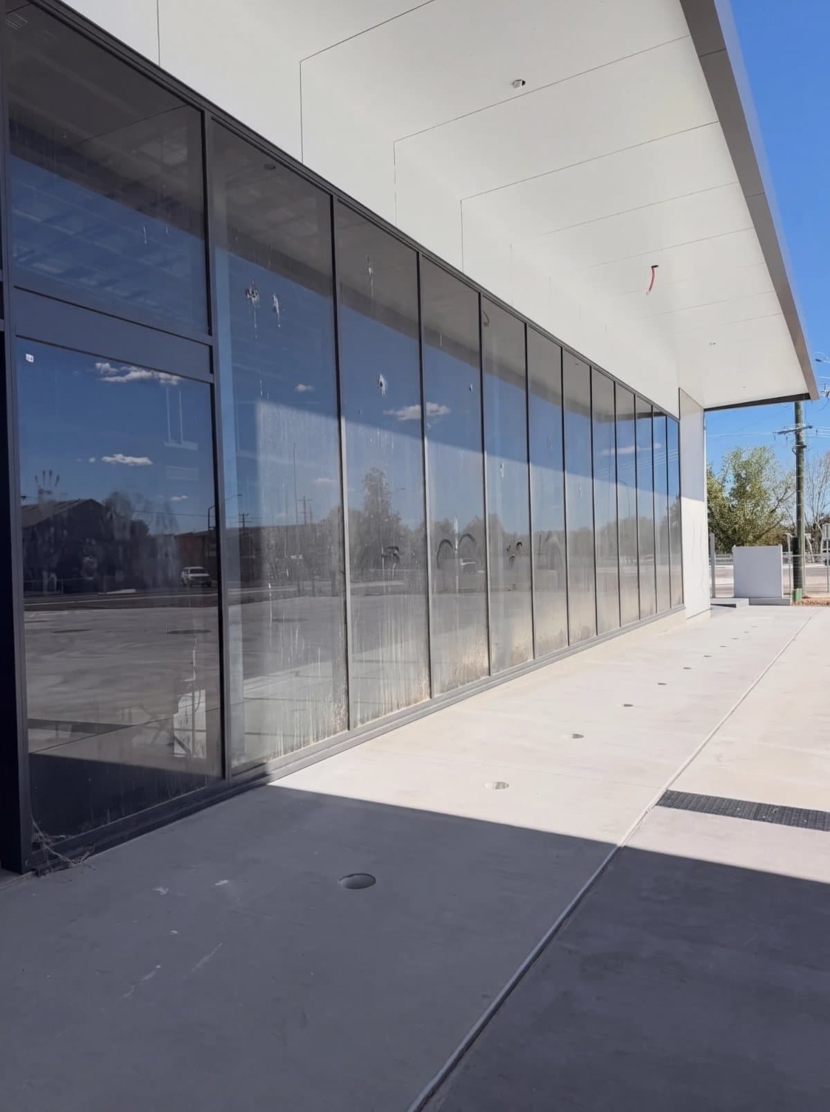 Illustrative example: a commercial glass shopfront with dusty, streaked, spotted windows, before cleaning